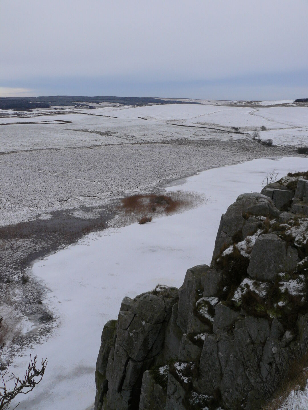 Frozen lake Crag Lough beneath the cliffs.