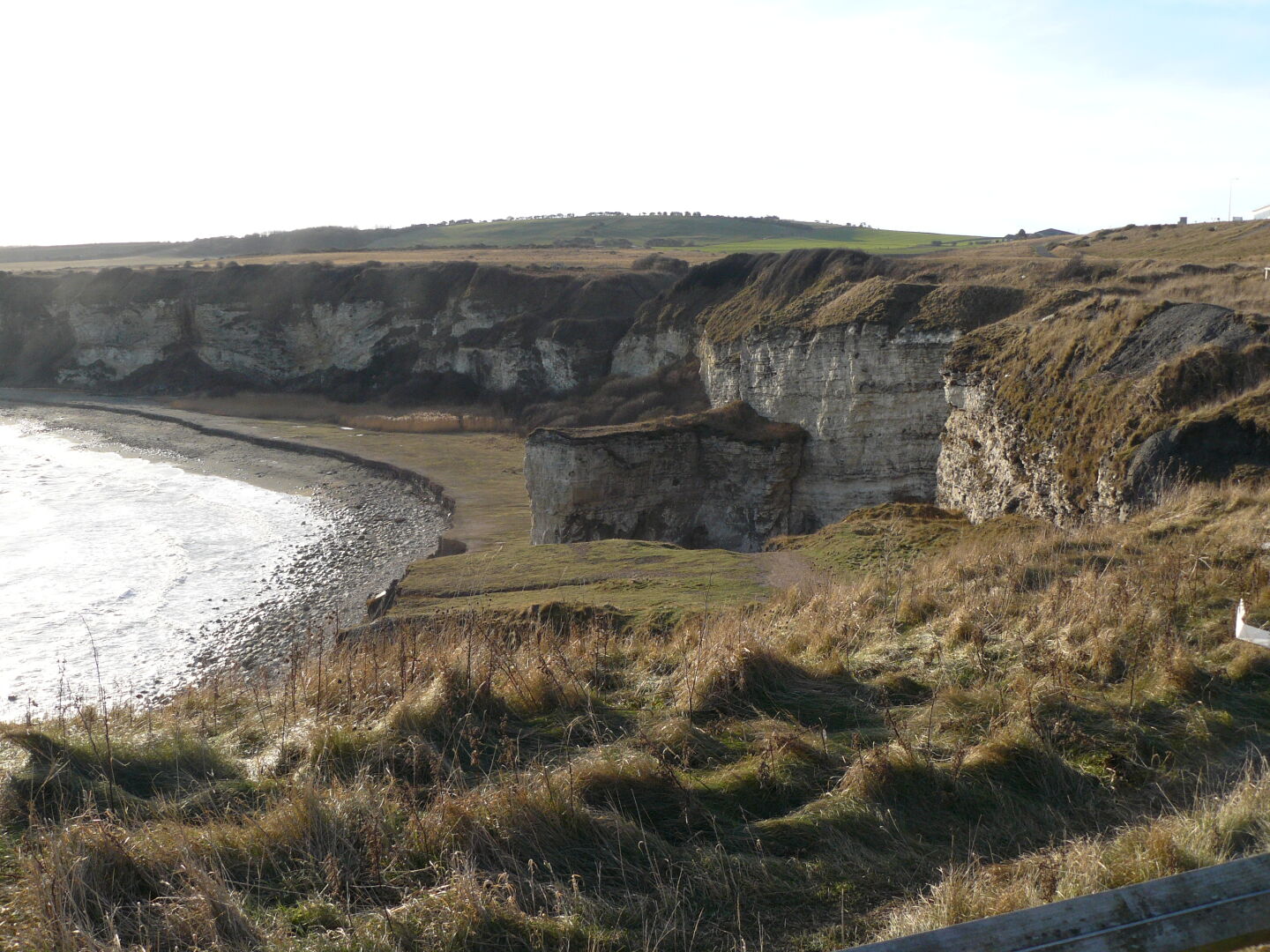 Steep cliffs surround a small beach. It&rsquo;s high tide right now.