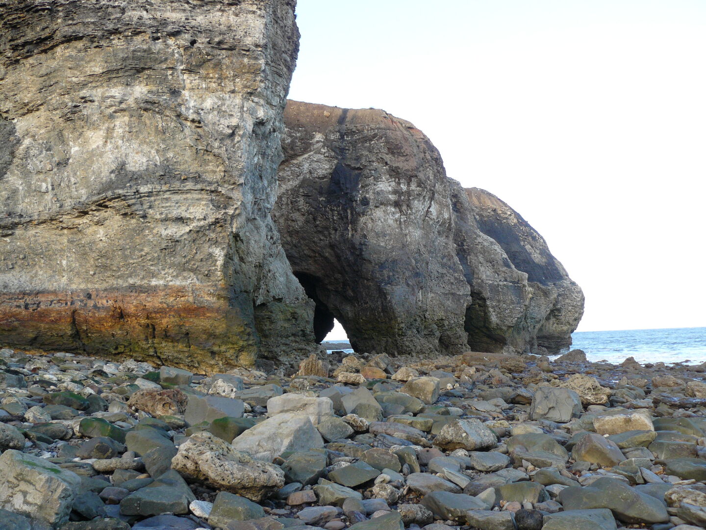 The continuous force of the sea has not only taken away most of the coal-mining trash, it has also created these arcs in the cliffs,