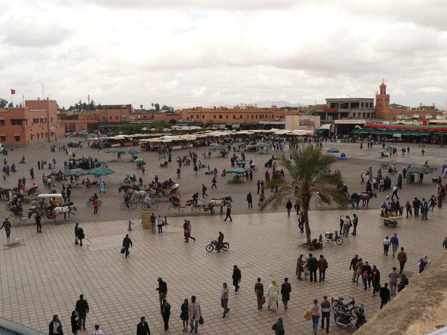 Blick auf den Platz Djeema al Fna mit Schlangenbeschwörern, Obstständen und Hennah-Frauen.