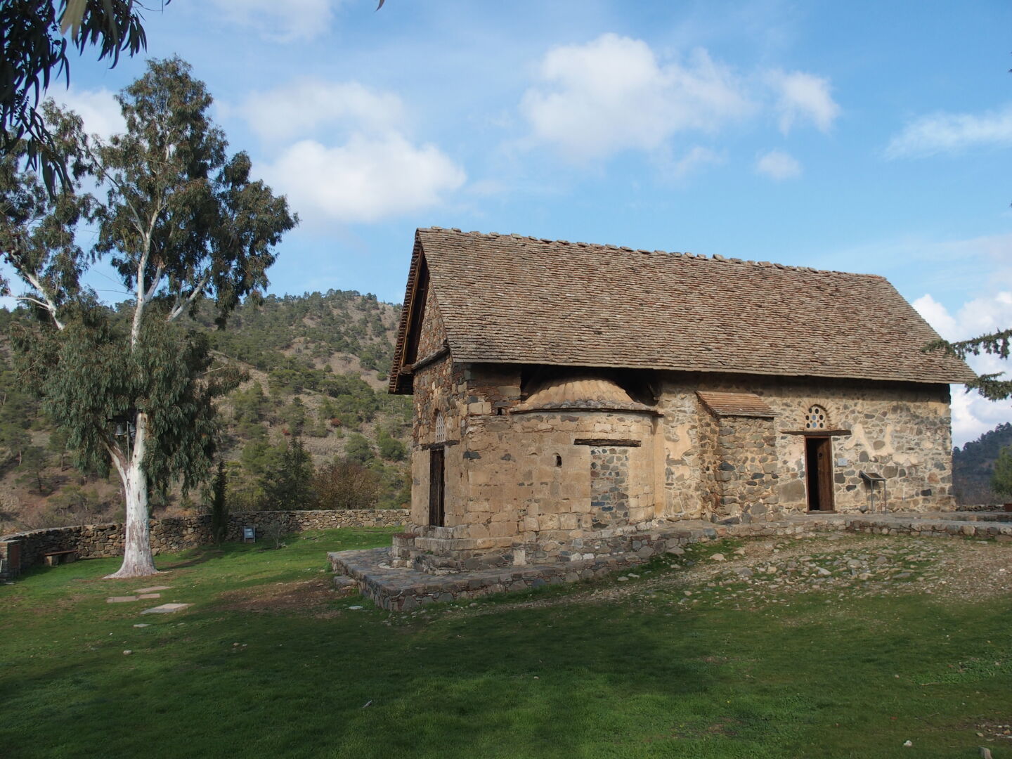 The chapel of Asinou. Note the bells in the eucalyptus tree. The plain roof disguises the church as a barn, deceiving potential robbers.