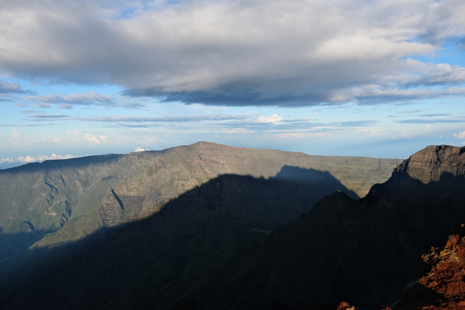 Blick vom Piton des Neiges auf den Piton de la Fournaise im Südosten. Blick nach Westen: Der Piton des Neiges wirft seinen Schatten auf den Rempart de Mafate.